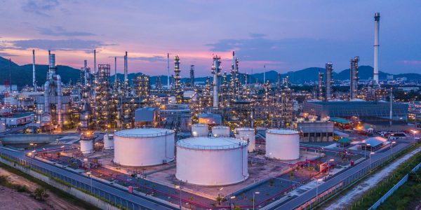Aerial top view oil and gas chemical tank with oil refinery plant background at twilight.