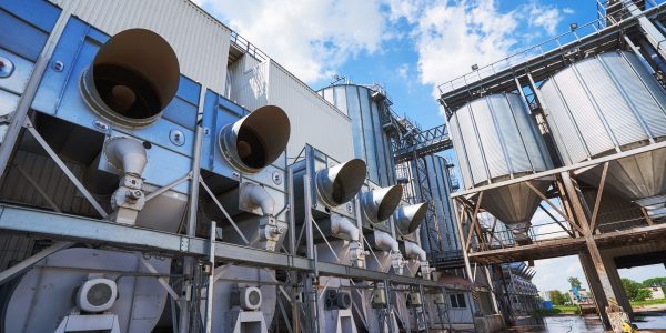 Agricultural Silos. Building Exterior. Storage and drying of grains, wheat, corn, soy, sunflower against the blue sky with white clouds.